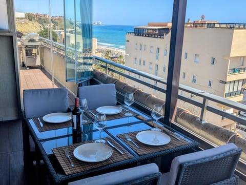 Glazed terrace with a table set for four, the sea and the coast behind